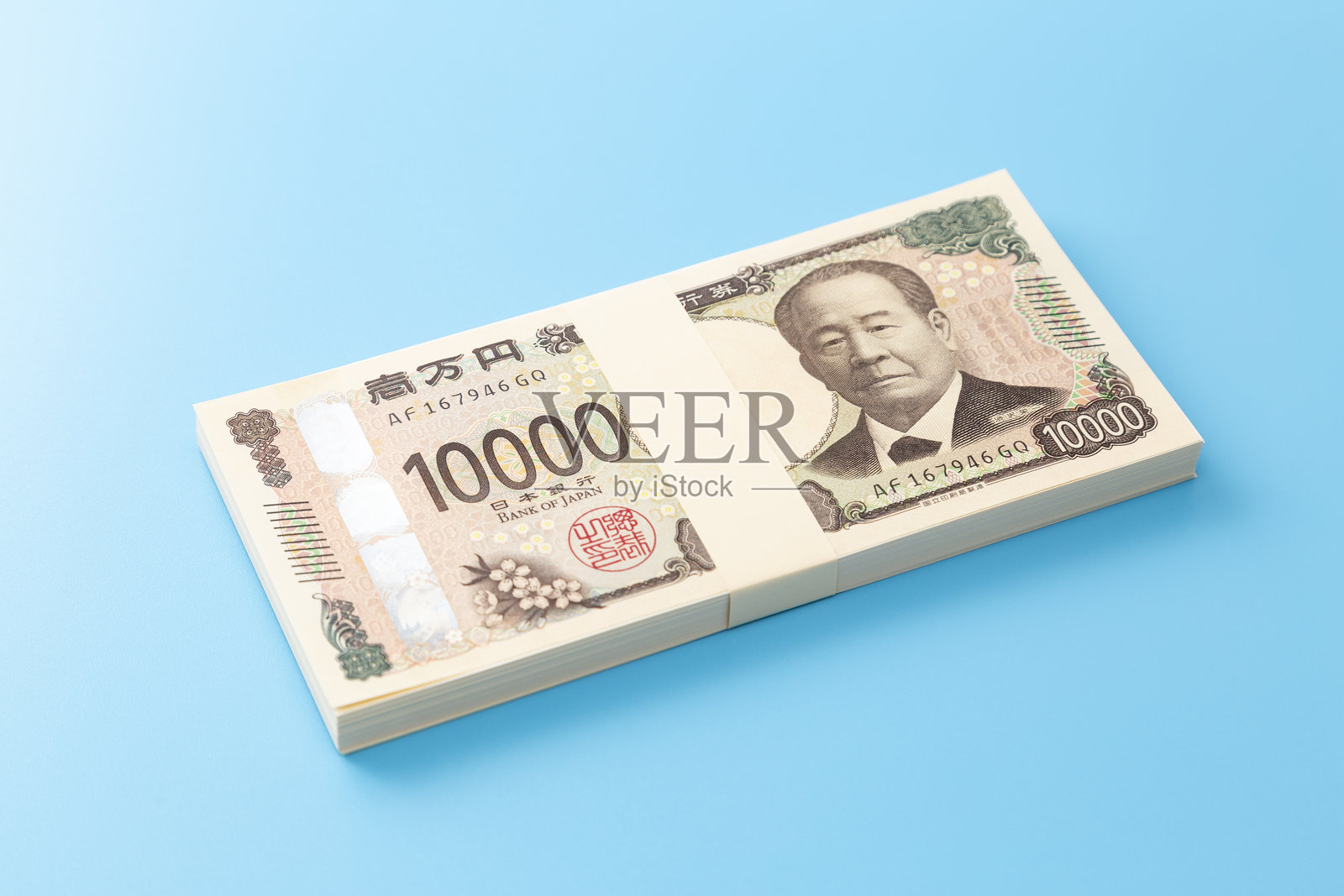 一叠10,000日元钞票放在蓝色背景上。照片摄影图片