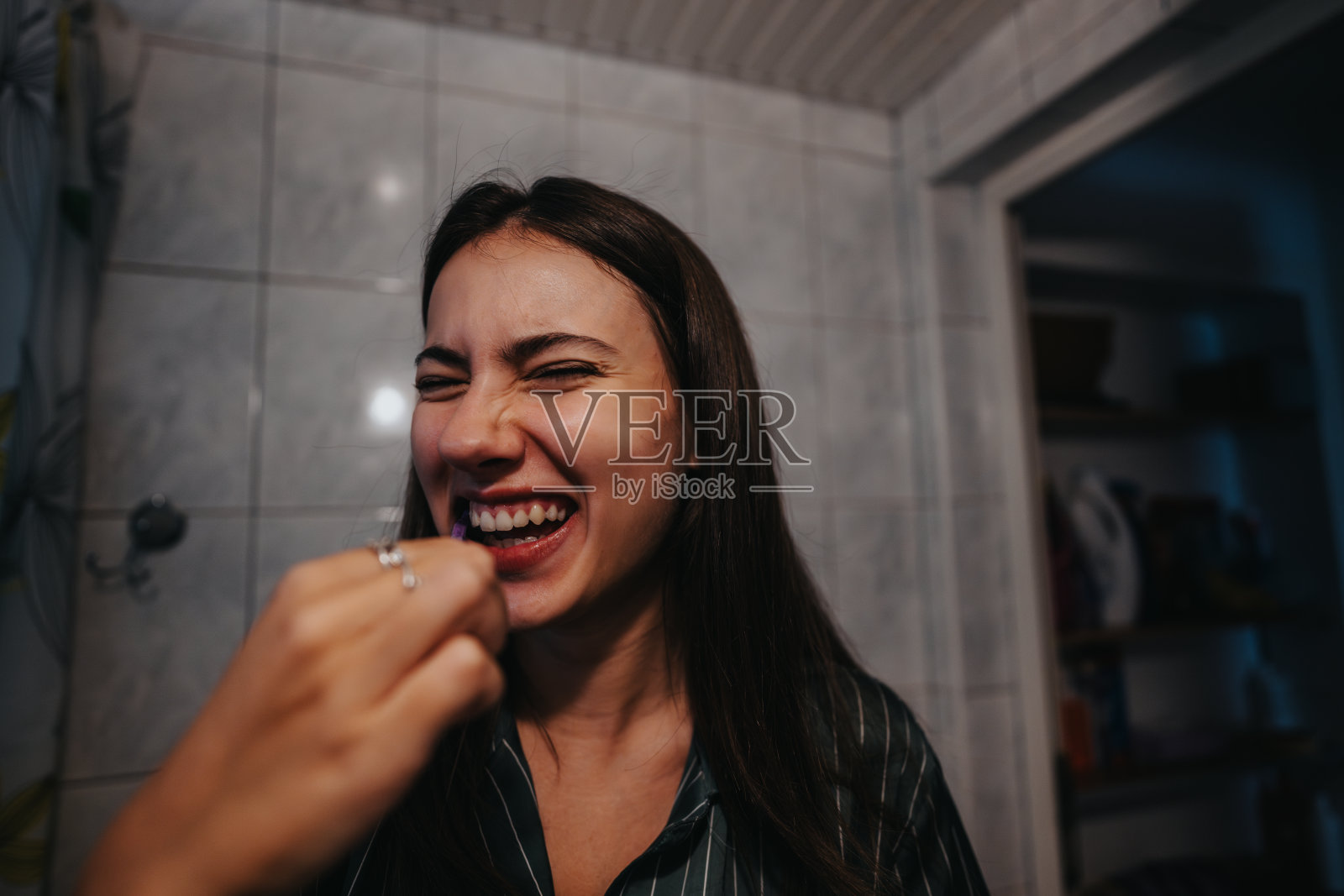 年轻女性早晨刷牙时快乐地大笑照片摄影图片