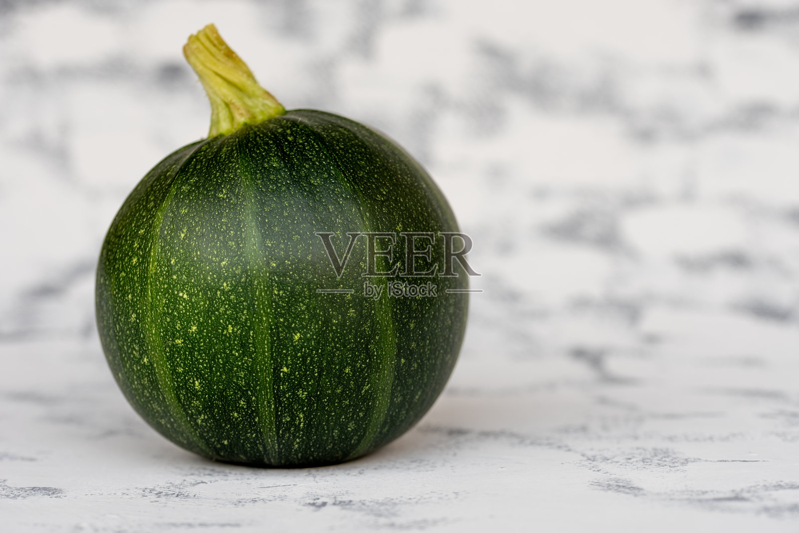 有机圆形绿色西葫芦在灰色乡村背景上。照片摄影图片