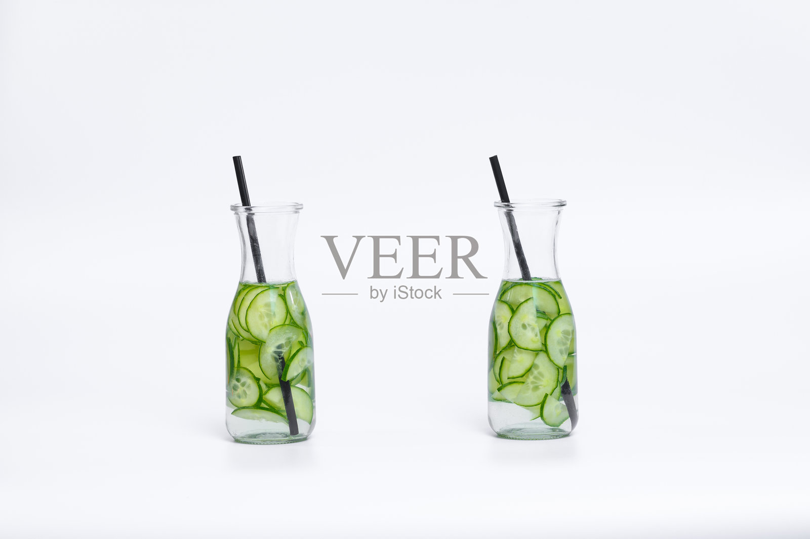 在白色背景上，加入新鲜绿色黄瓜的水照片摄影图片