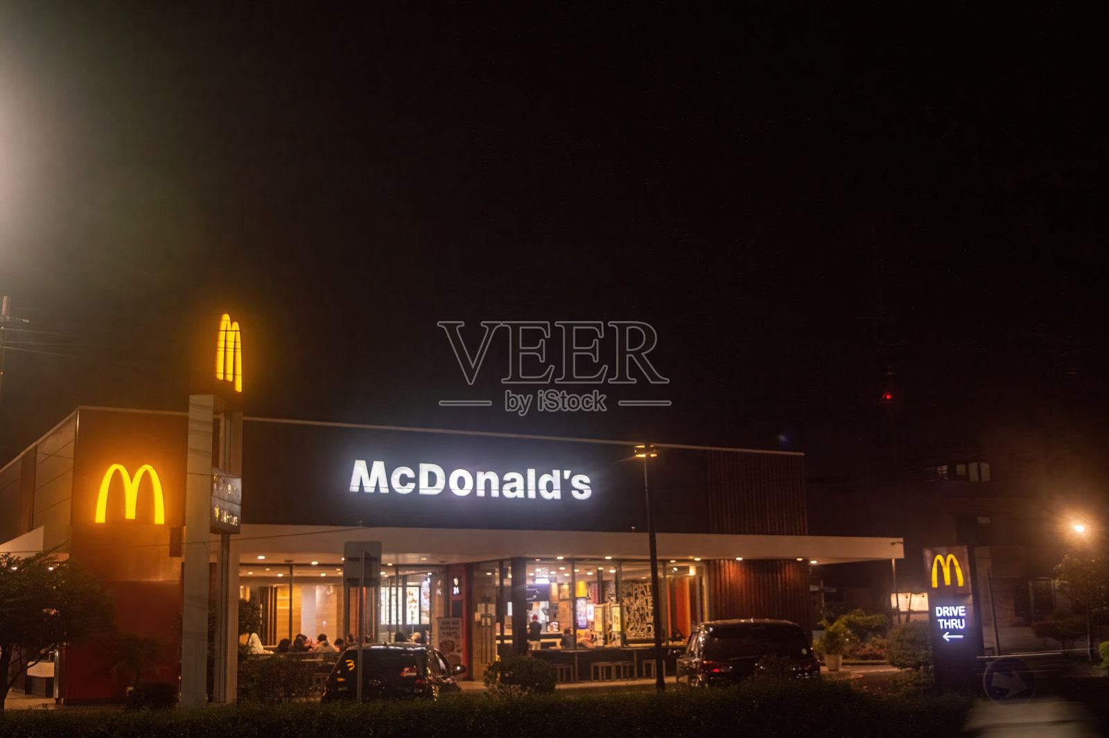 一家明亮的麦当劳餐厅在夜晚,显眼的标识和自驾取餐窗口,展示标志性的金色拱门,印度尼西亚,2024年11月4日。照片摄影图片