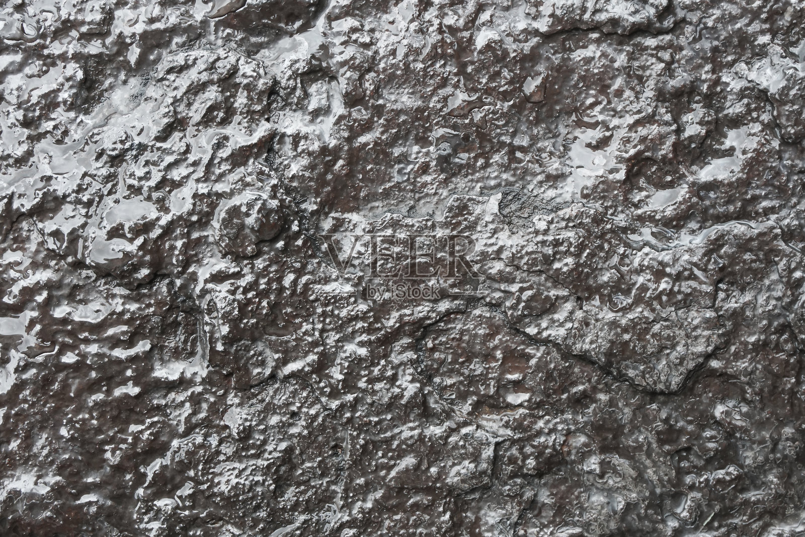 湿润的岩石背景。光滑石头的粗糙纹理。钢铁般的外观。划痕和粗糙的表面。照片摄影图片