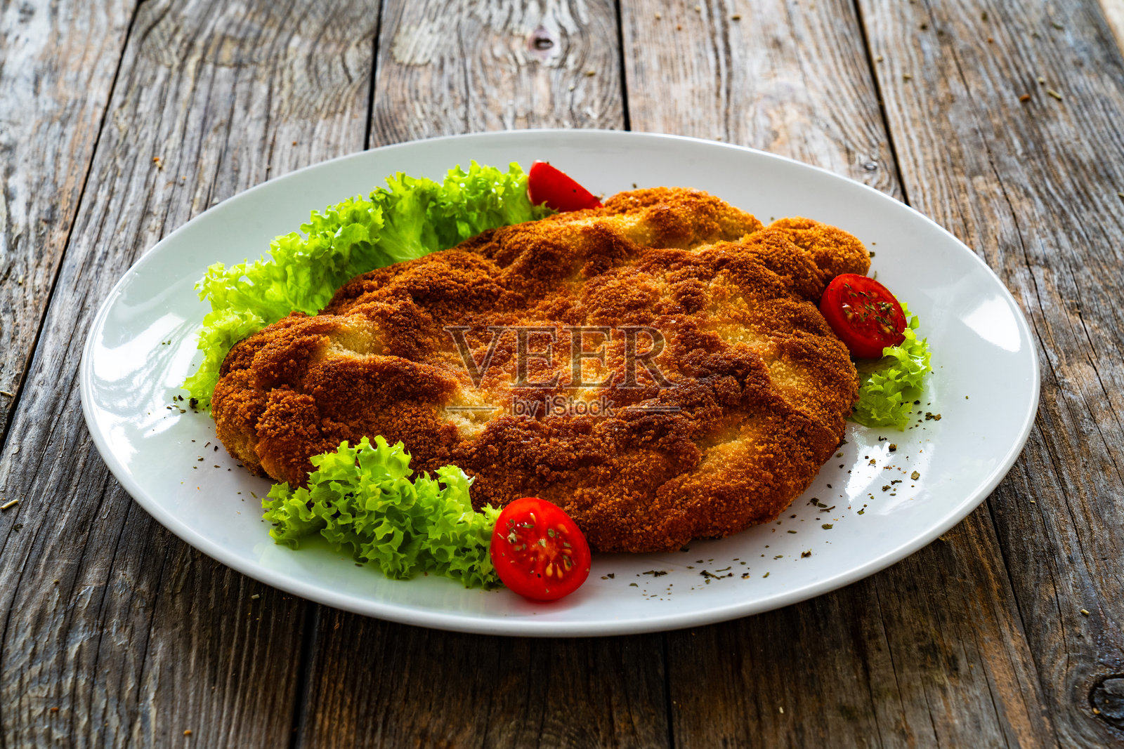 面包裹炸猪排配生菜和番茄，放在木桌上照片摄影图片