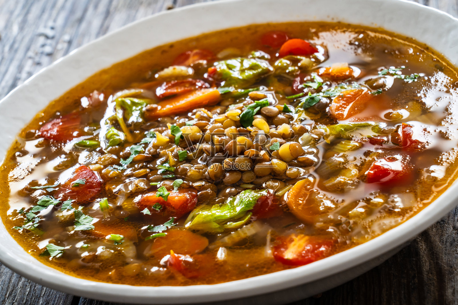 新鲜蔬菜扁豆汤盛在白色碗中，放在木桌上照片摄影图片