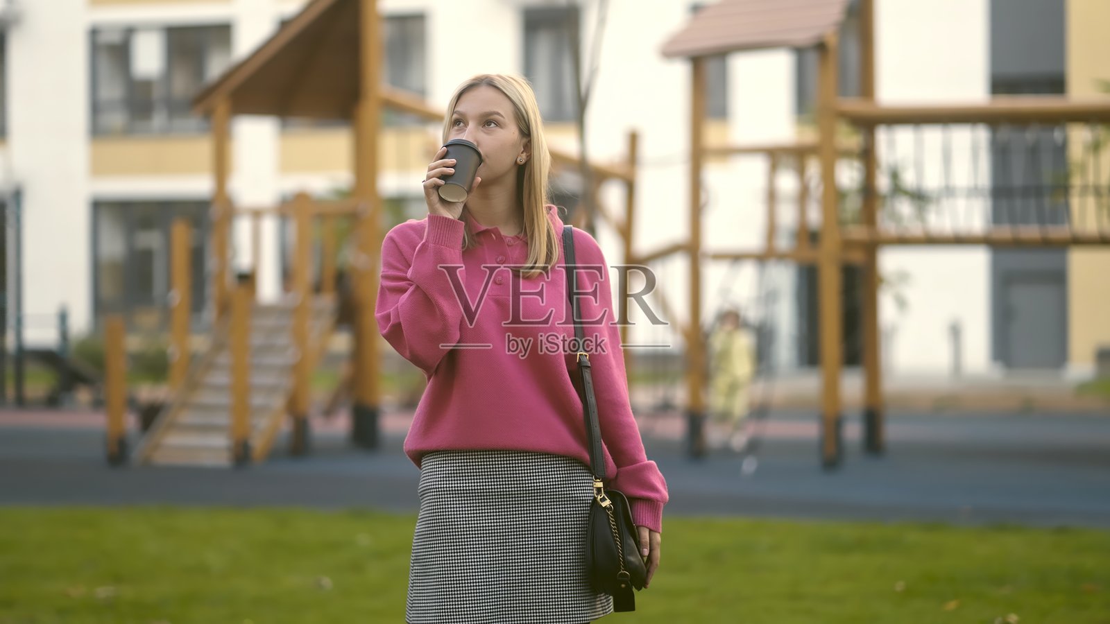 一位女性在城市游乐场区域享受一杯咖啡。照片摄影图片