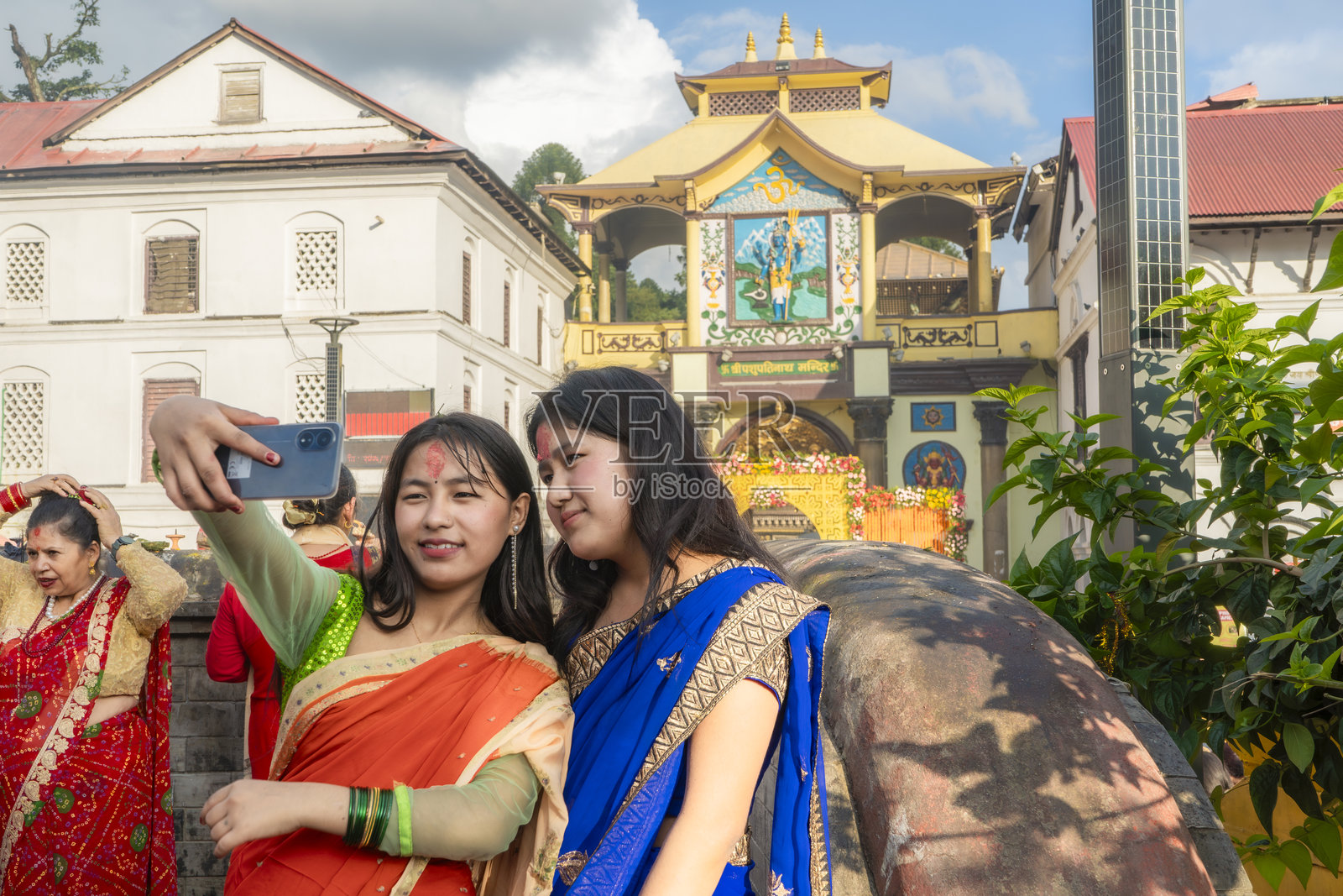 尼泊尔加德满都帕斯帕提纳特寺的尼泊尔教徒女性穿着红色服装庆祝提吉节并跳舞。照片摄影图片