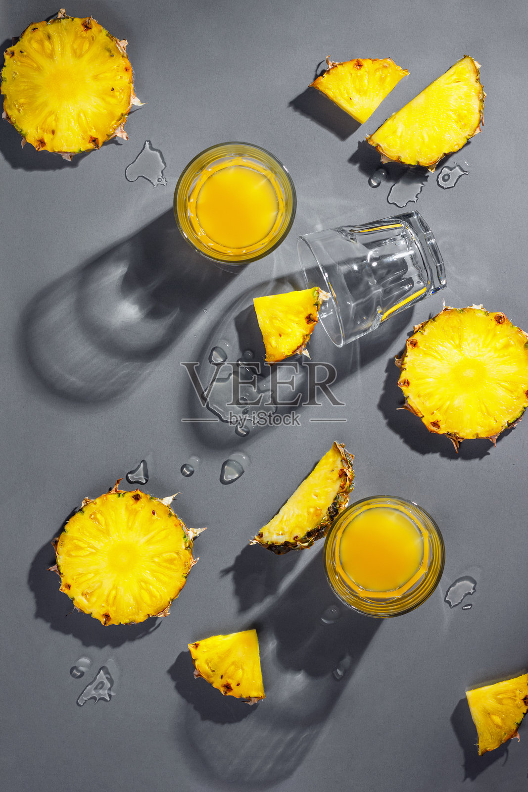 菠萝块和菠萝汁在灰色背景上隔离。热带假日概念照片摄影图片