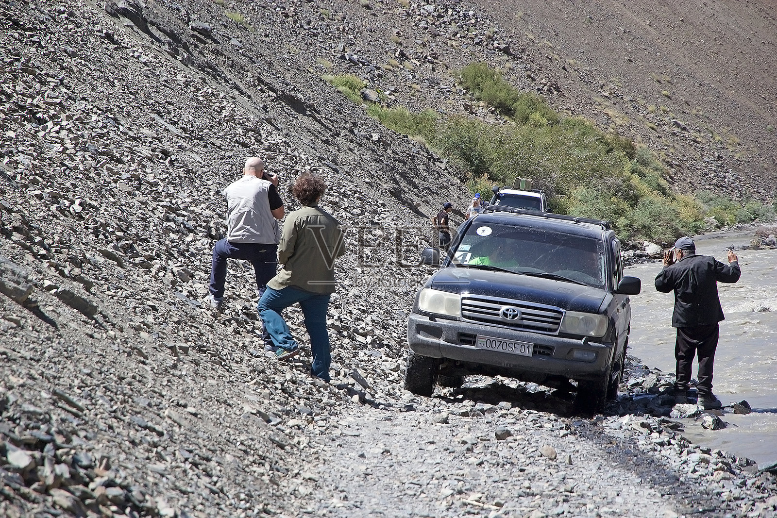 越野车沿着部分被河流吞没的轨道行驶，穿过塔吉克斯坦的戈尔诺-巴达赫尚地区的巴尔唐谷。照片摄影图片