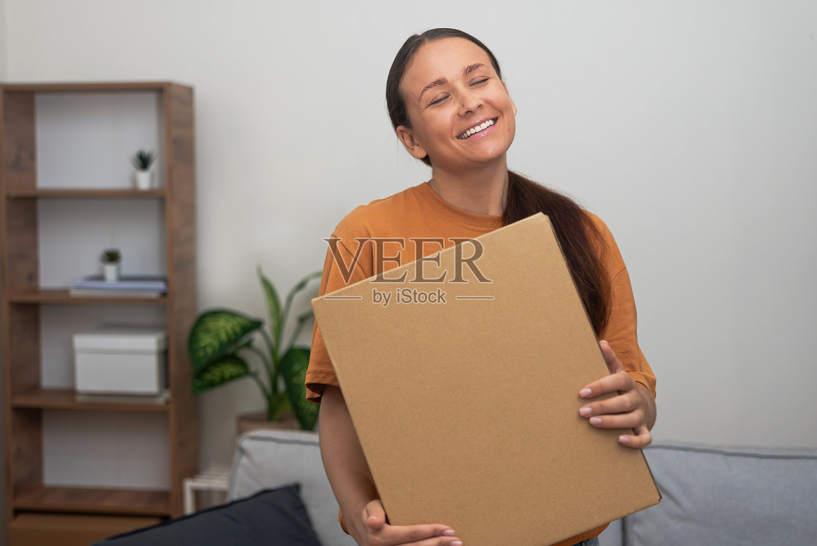 她手中拿着纸板包裹，承载着一位女性收到心仪网购订单的快乐。照片摄影图片