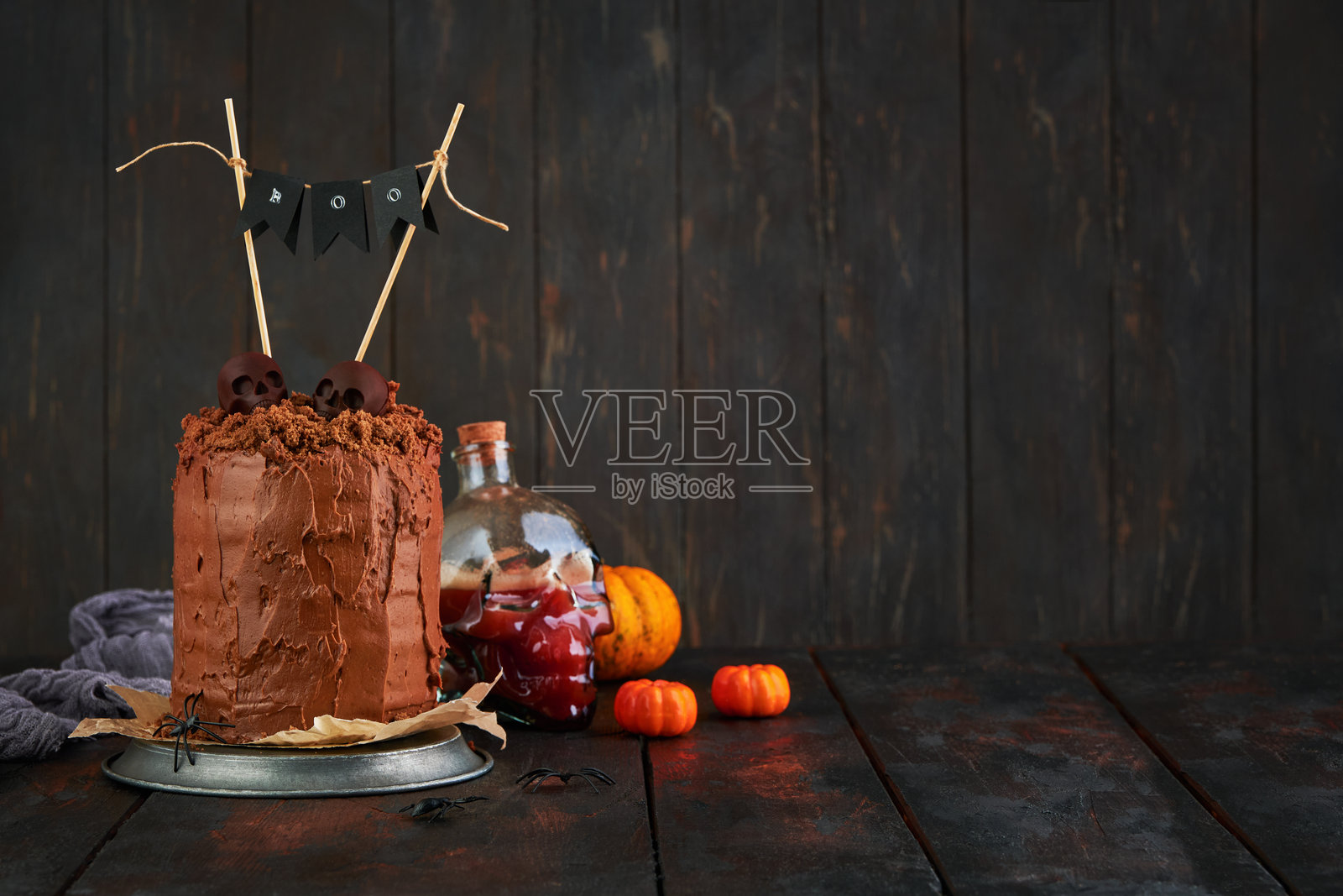 幽灵般又搞笑的巧克力蛋糕，层叠着布朗尼，配有土壤状的碎屑，装饰着黑白巧克力骷髅、光秃的老树枝和干枯的落叶。适合万圣节派对的甜蜜搞笑创意，留有空白空间。照片摄影图片