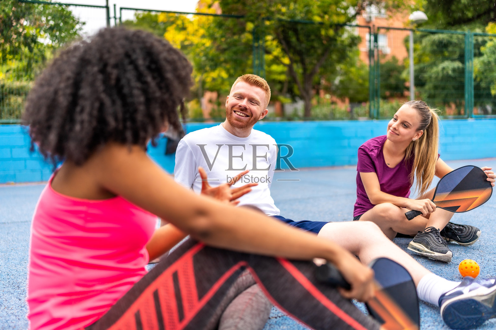 女人在球场上打完皮克球后与朋友交谈照片摄影图片