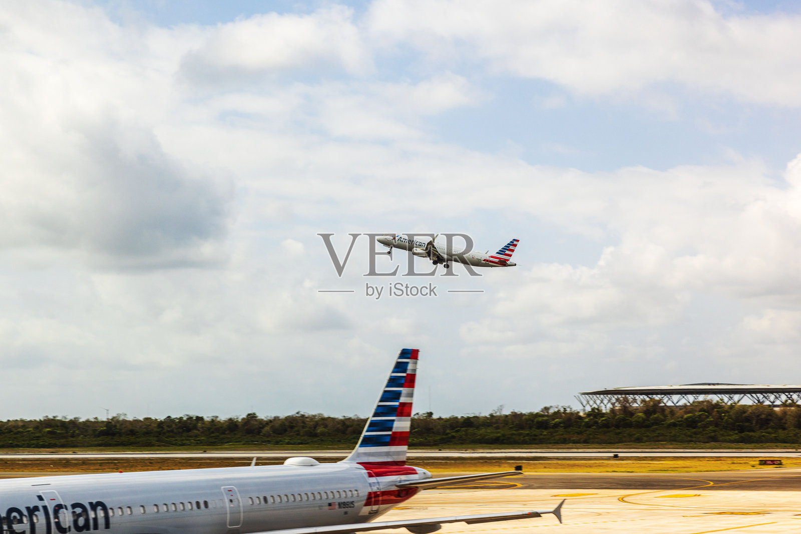 美国航空公司飞机在坎昆国际机场起飞，另一架飞机停在停机坪上。照片摄影图片