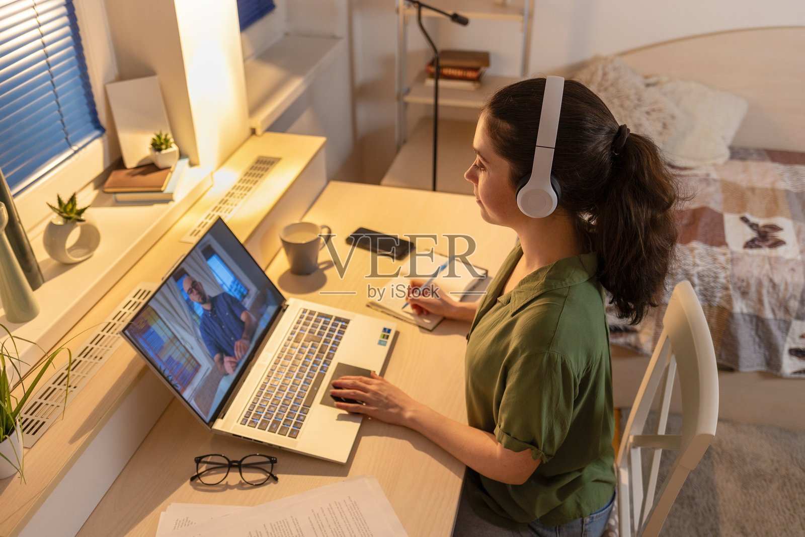 从上方看年轻女性在使用笔记本电脑并佩戴耳机。自由职业和在线教育。与心理治疗师的远程咨询。照片摄影图片