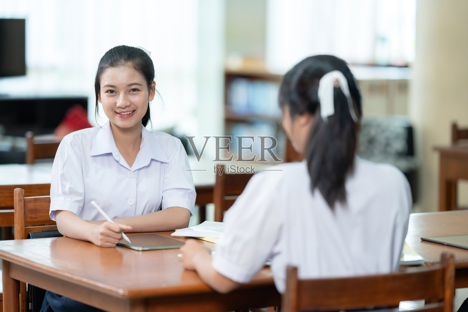 怀着坚定的决心，长发的亚洲高中女孩在图书馆里花时间学习她知道能提供宝贵见解和必要知识的书籍。照片摄影图片