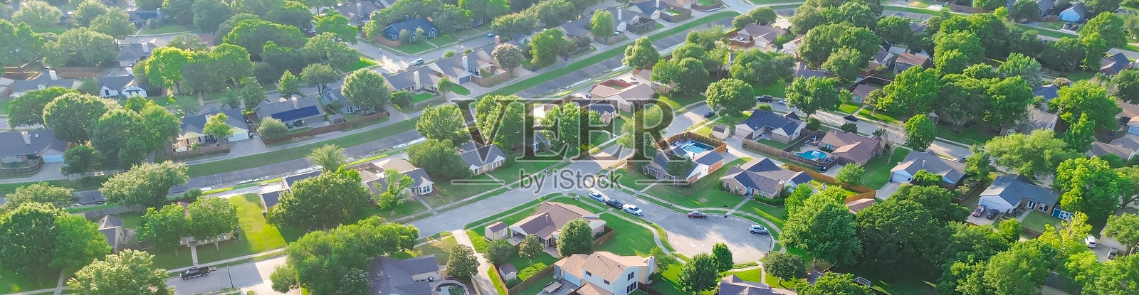 德克萨斯州科佩尔达拉斯-沃斯堡大都会区郁郁葱葱的住宅区中的排水混凝土渠道，独立单户住宅排成一排，游泳池，大后院，草坪。照片摄影图片