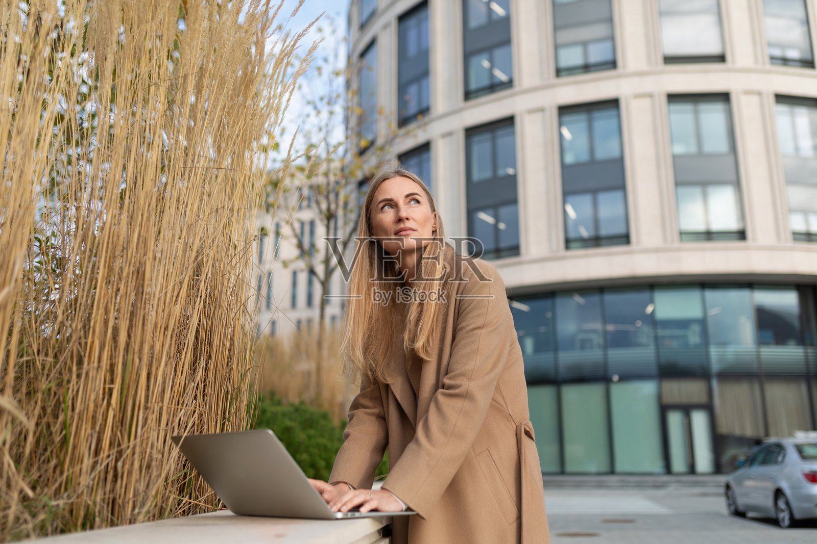 一位女商人在商务中心外使用笔记本电脑，休息时思考下一步行动。照片摄影图片