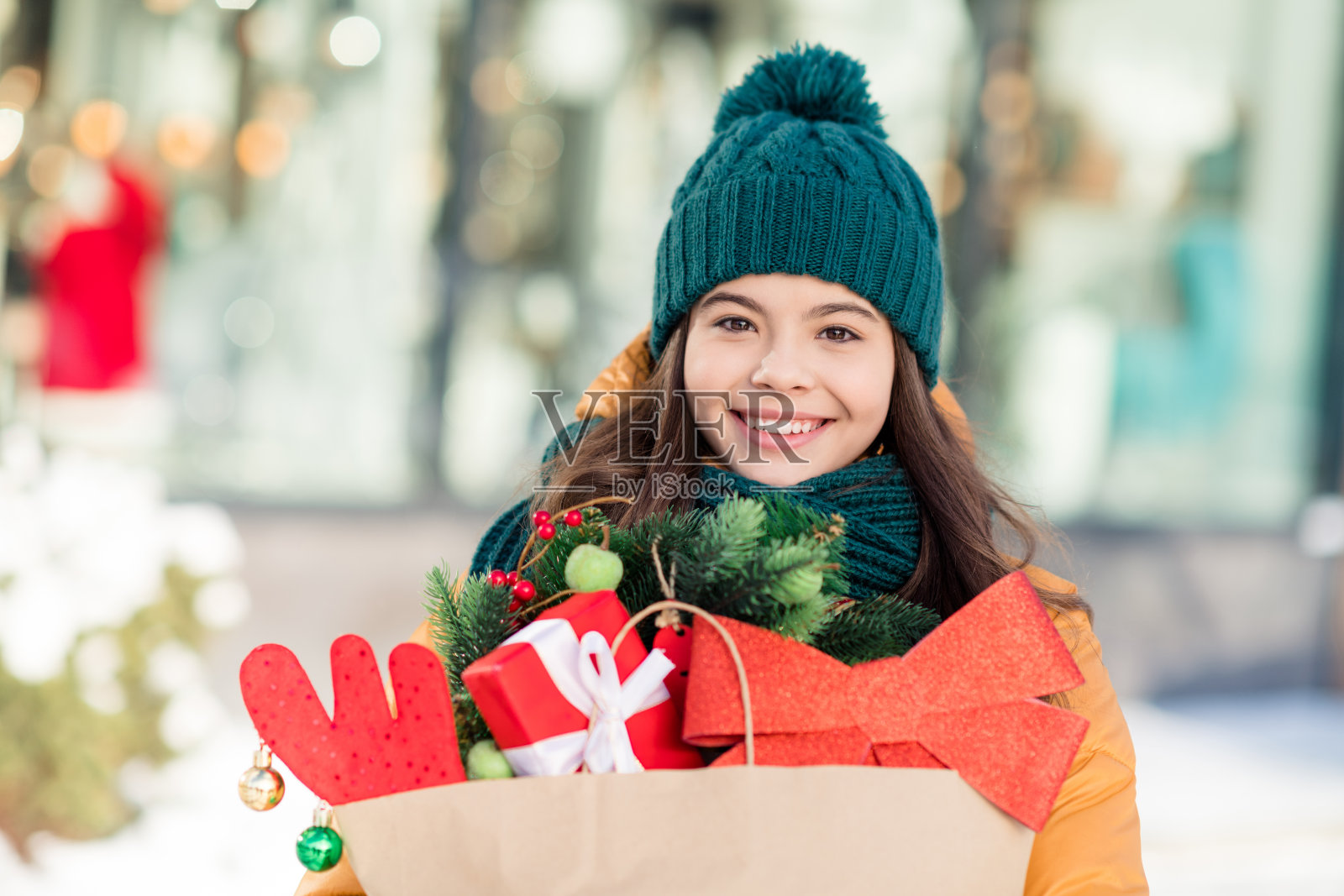 穿风衣的快乐搞笑女学生在城市街道上购买圣诞礼物的照片照片摄影图片