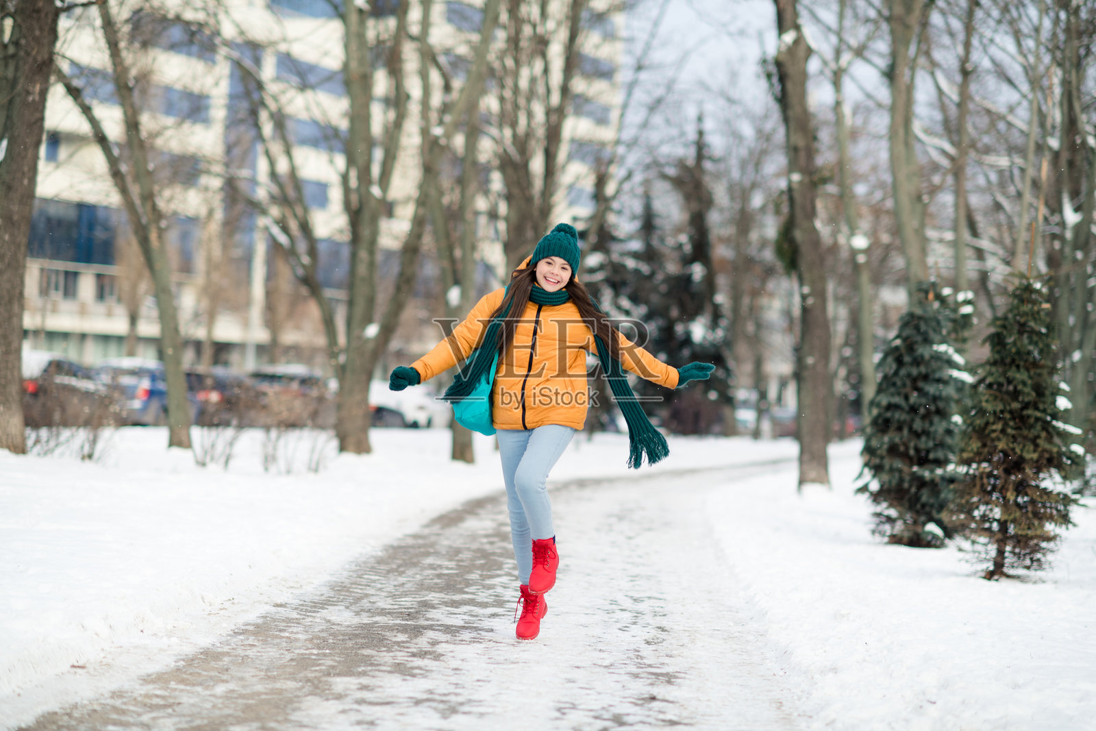 全身身材的迷人、快乐、时尚女孩穿着温暖的服装，在户外雪天跳跃玩耍。照片摄影图片