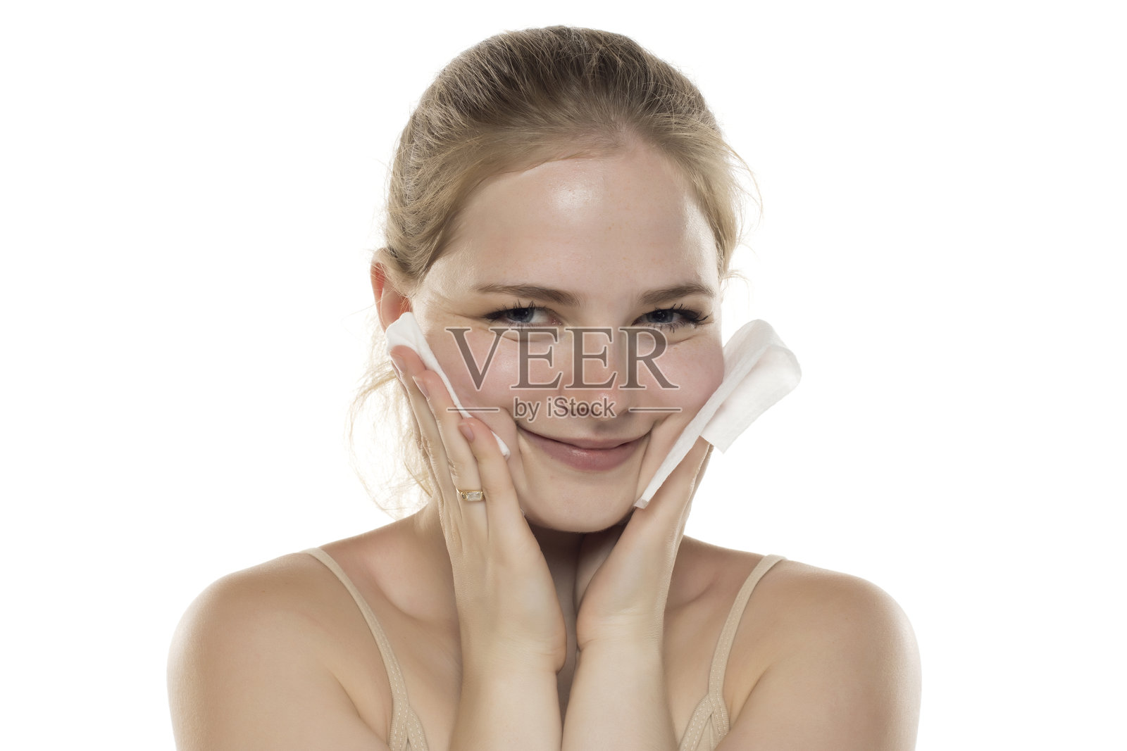 年轻微笑的女性在白色摄影棚背景下卸妆的肖像。照片摄影图片