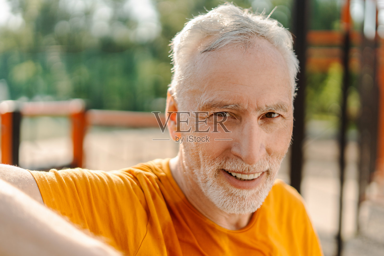 老年男子微笑着在户外的健身器材上享受锻炼照片摄影图片