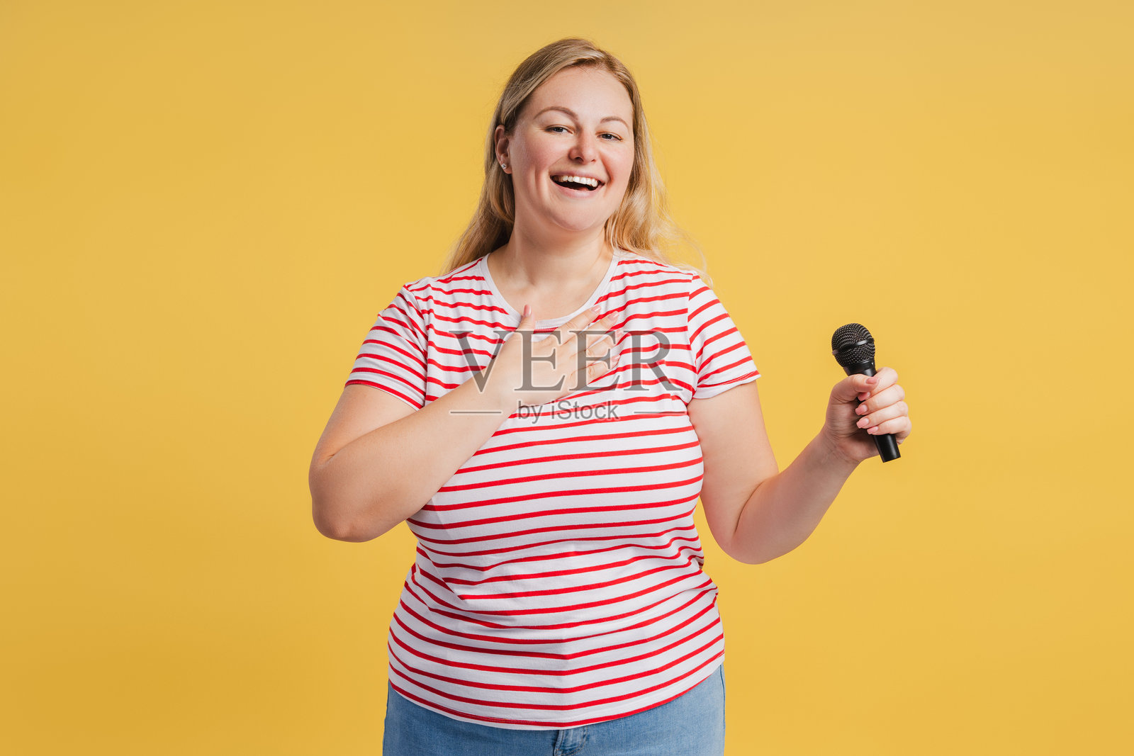 快乐的胖女性在黄色背景下手持麦克风准备唱歌照片摄影图片