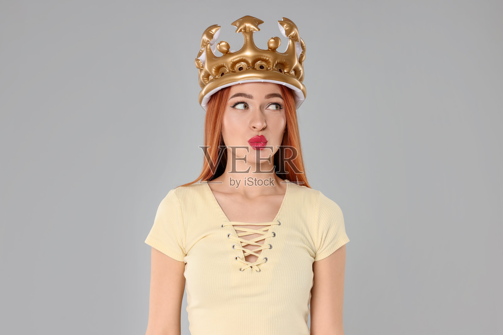 美丽的年轻女性戴着充气王冠，背景为浅灰色照片摄影图片