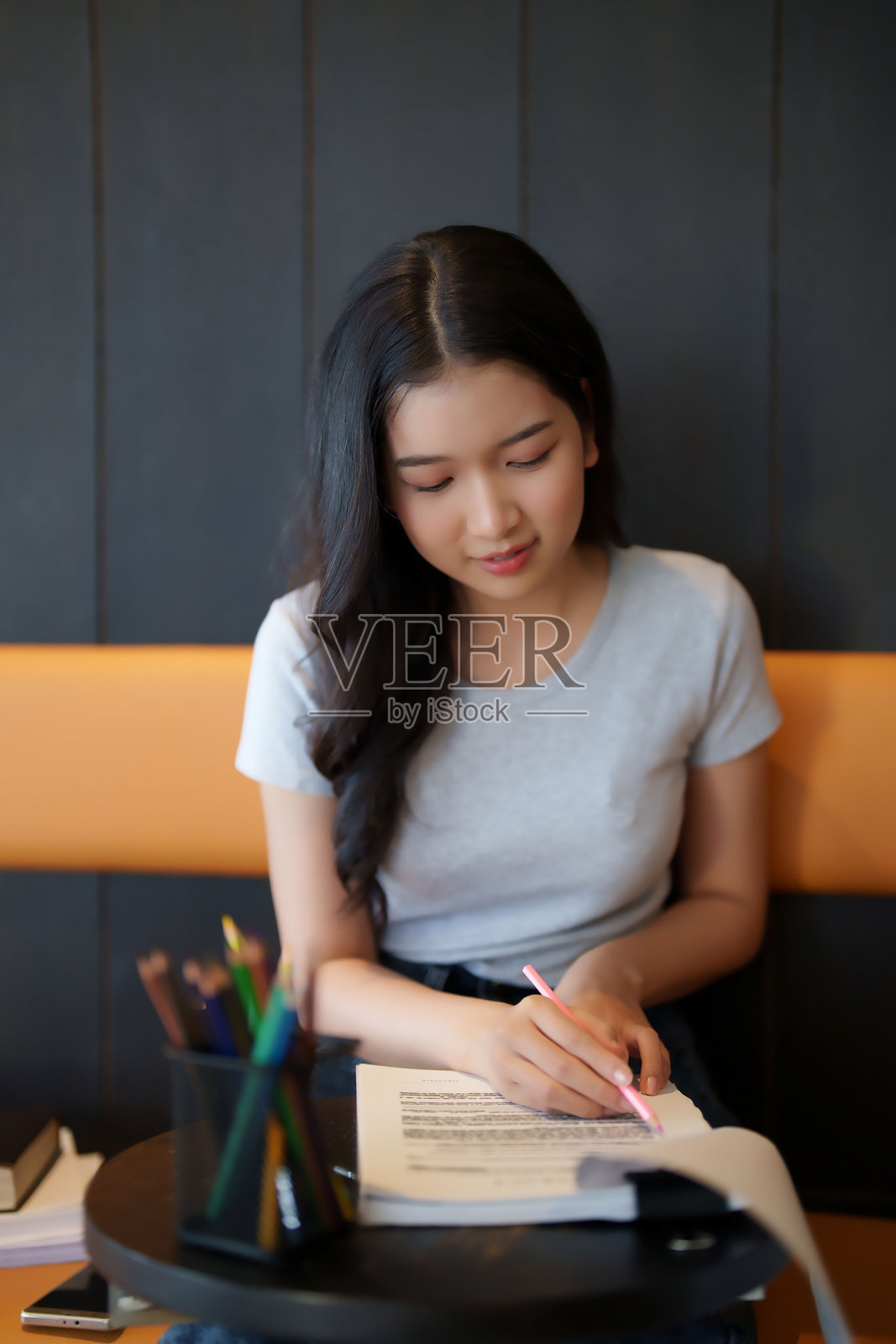 亚洲女学生在咖啡馆阅读文件信息，做笔记并完成作业，为考试准备学习知识。照片摄影图片