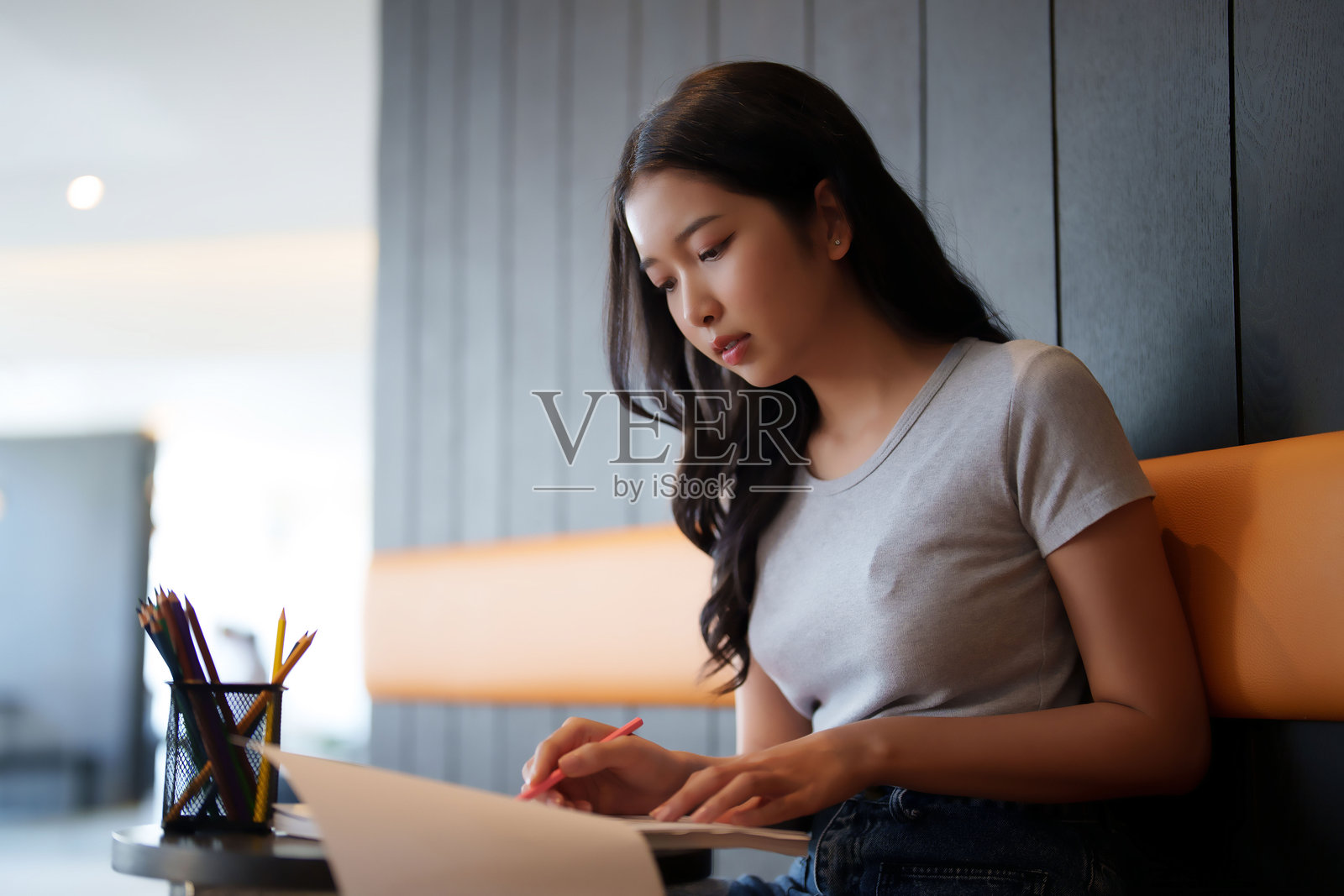 亚洲女学生在咖啡馆阅读文件信息，做笔记并完成作业，为考试准备学习知识。照片摄影图片