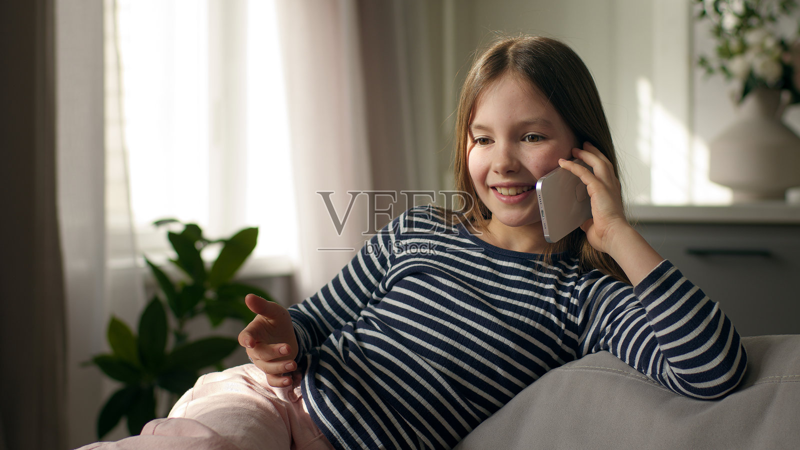 小女孩在家中用手机聊天，笑着与人沟通，享受这段对话。照片摄影图片