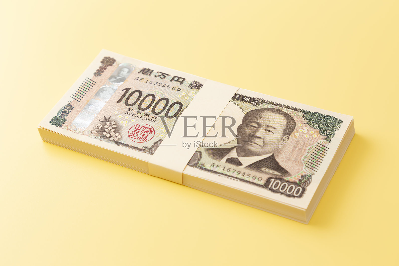 一叠10,000日元钞票放在黄色背景上。照片摄影图片