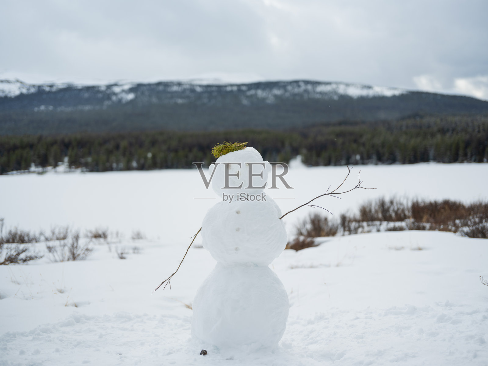 雪人问候，背景是山中的冰冻湖泊照片摄影图片