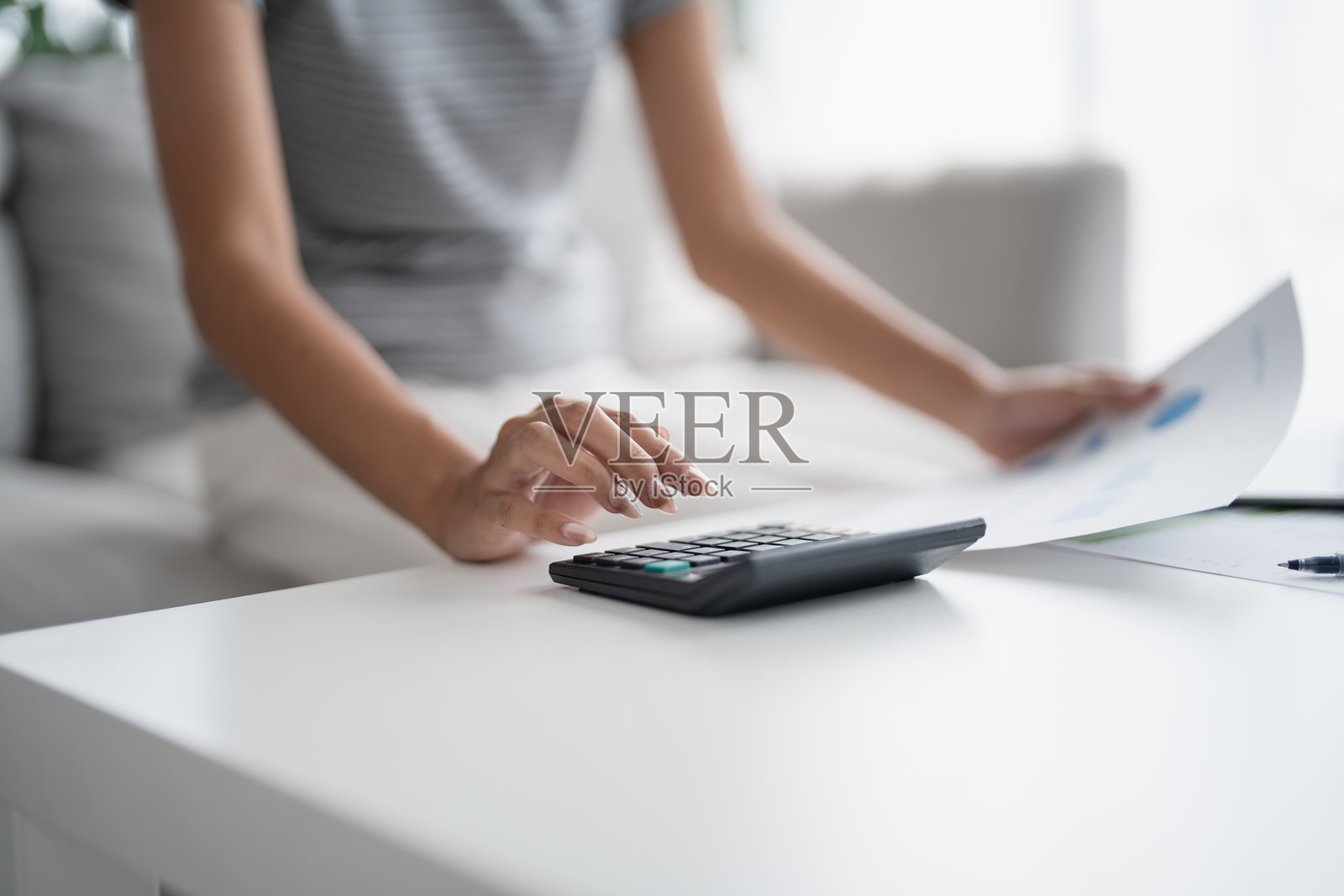 亚洲女性在家中远程使用计算器进行财务规划。照片摄影图片