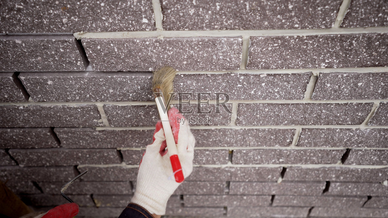 用刷子清洁房屋的外立面。对房屋的外立面进行填缝。工人用刷子清除房屋外立面上瓷砖残留的溶液。照片摄影图片