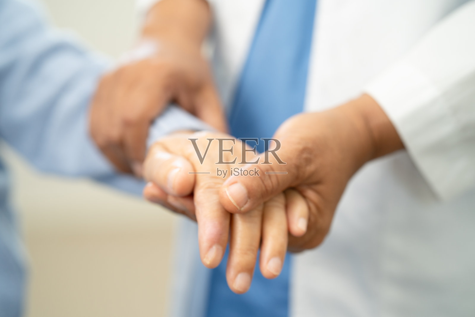 医生握着亚洲老年女性患者的手，在医院提供帮助和关怀。照片摄影图片