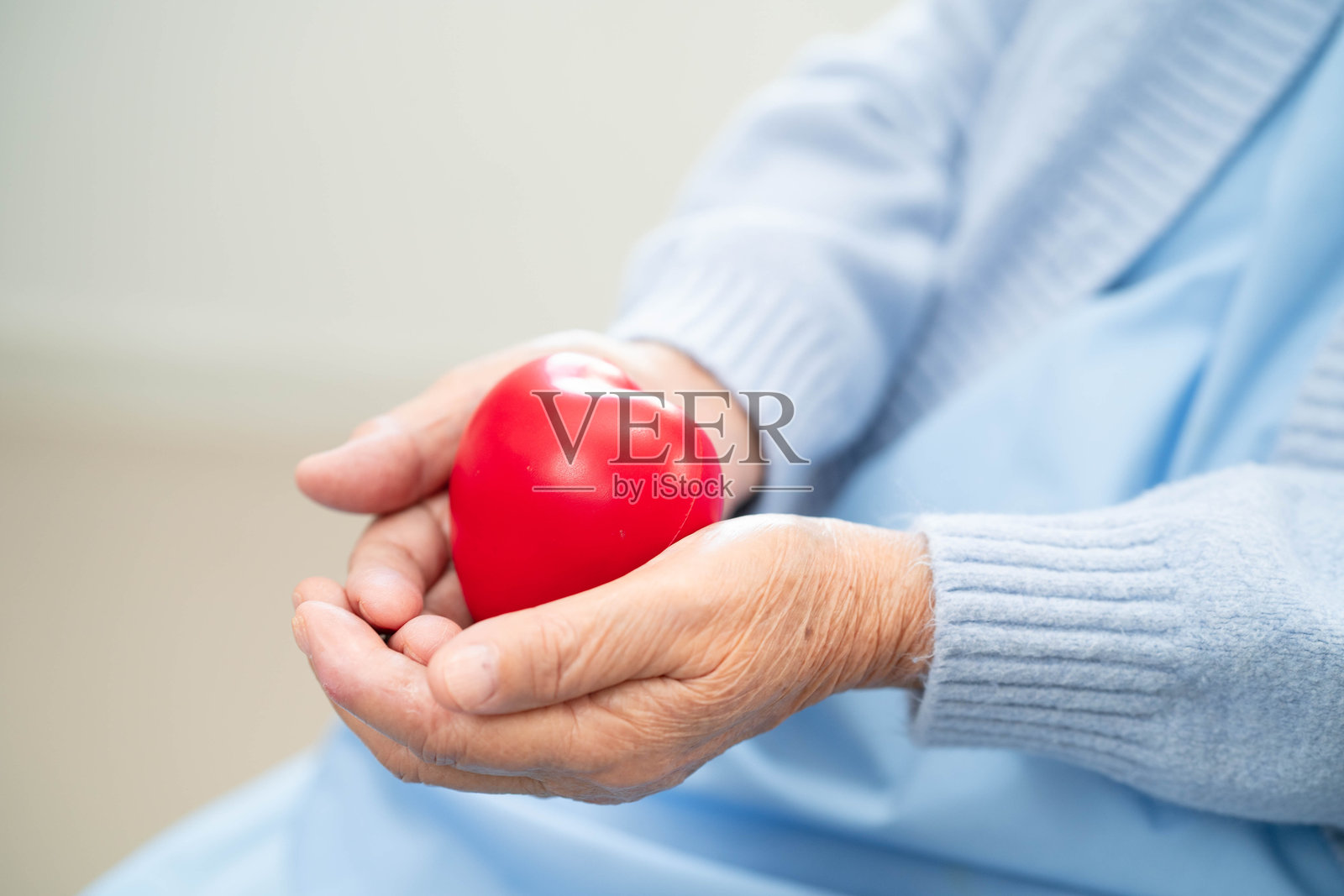 亚洲老年女性患者在医院里手握红心。照片摄影图片