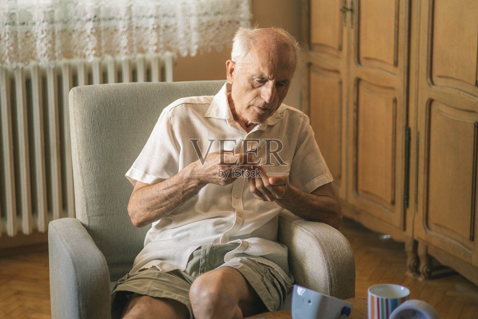 老年男子在家测量血压后服用药物和维生素。风湿病，止痛药。照片摄影图片
