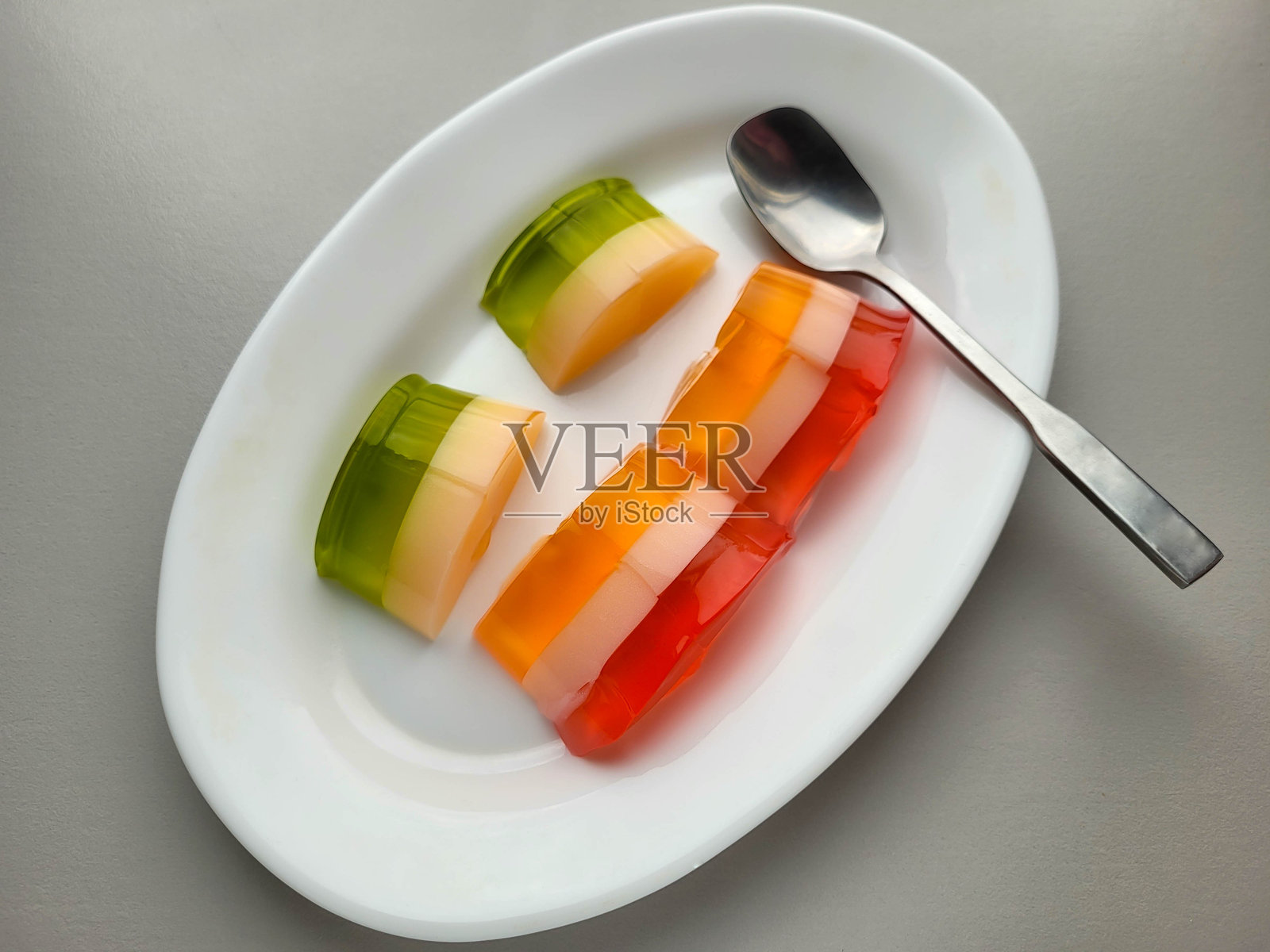 五颜六色的美味果冻摆放在白色椭圆盘上。照片摄影图片