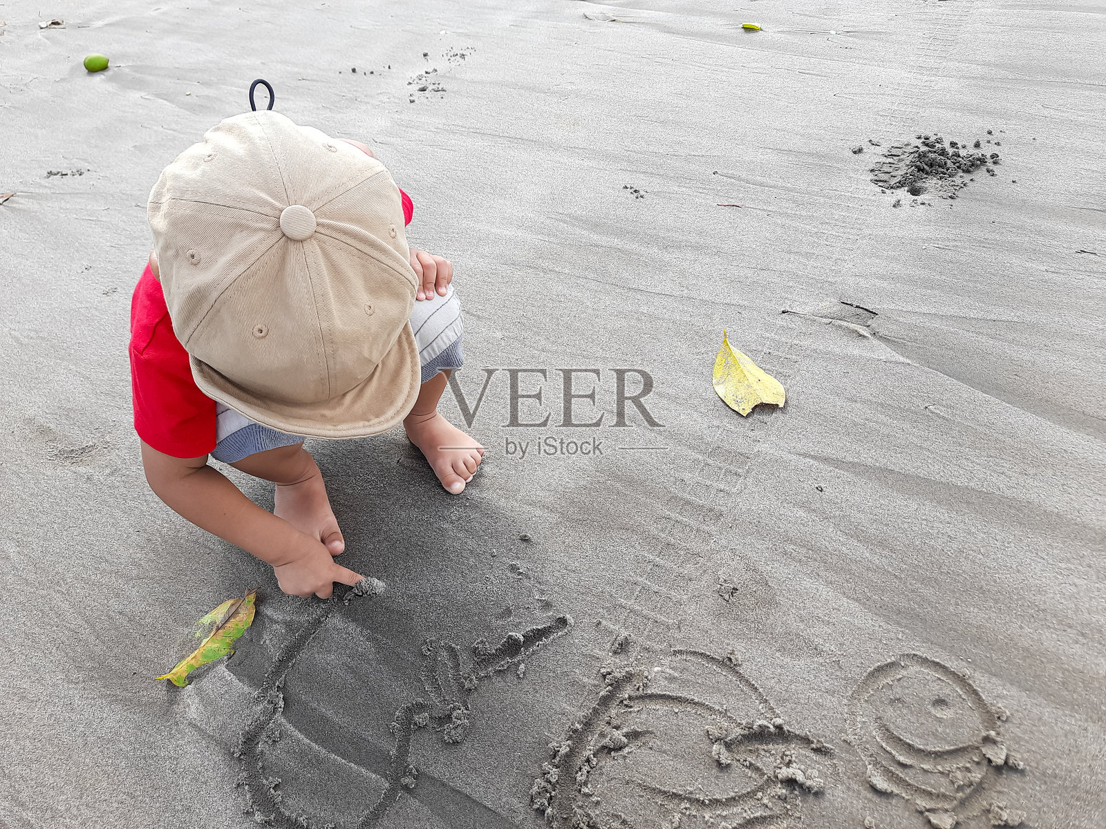 孩子在海滩上用沙子画画照片摄影图片