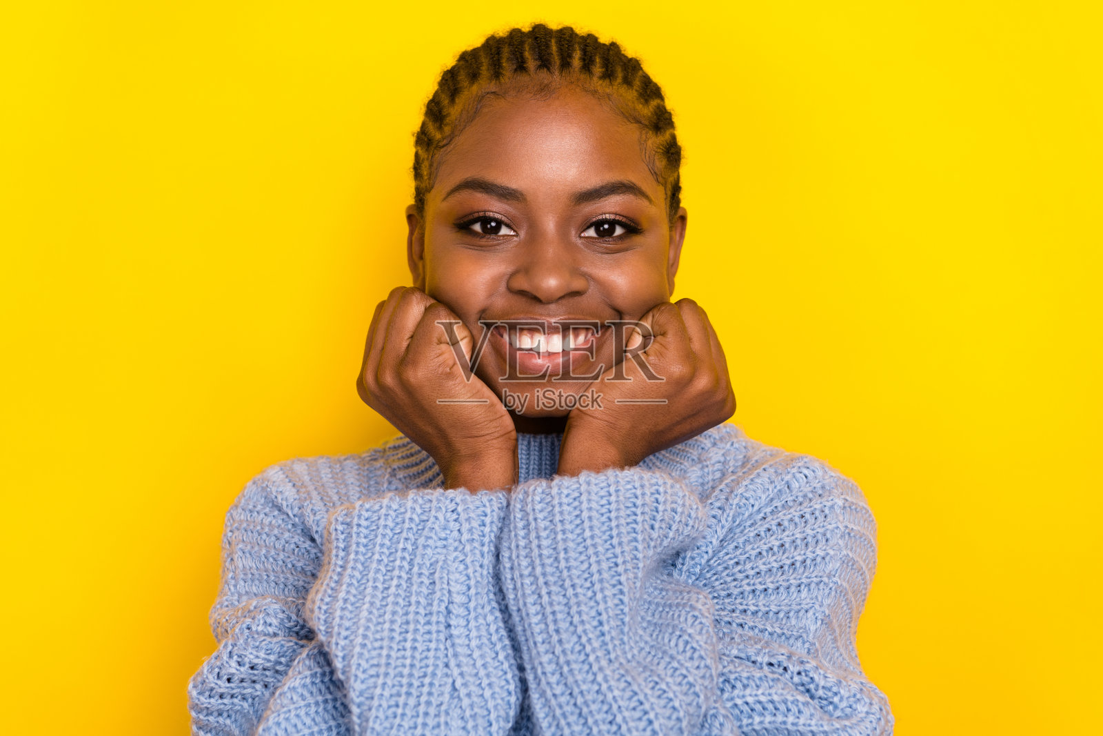 特写照片：年轻可爱的女孩微笑着，双手托着头，直视你，背景为黄色。照片摄影图片