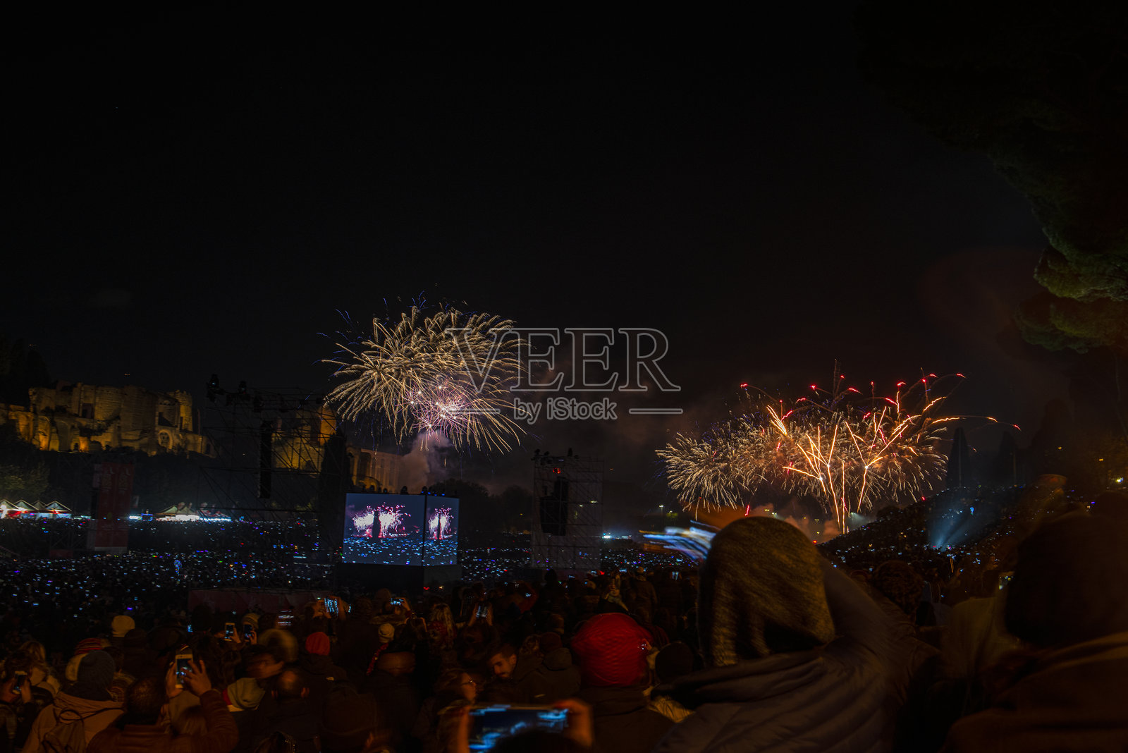 罗马广场的新年夜庆祝活动。夜间照片，烟花绽放，众多手持手机拍摄烟花的人群。罗马，意大利。照片摄影图片
