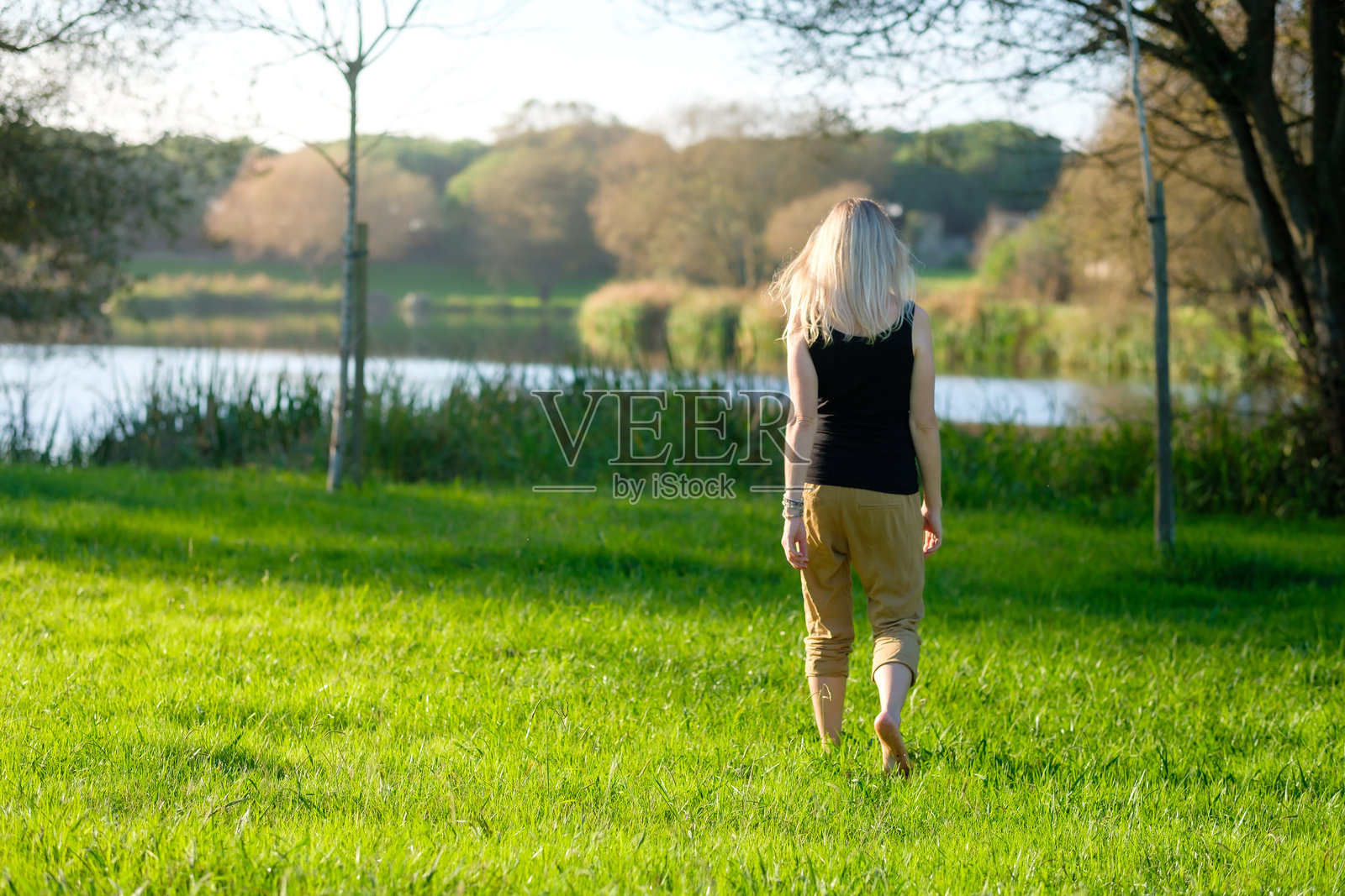 赤脚在草地上行走的女人。接地/大地疗法照片摄影图片