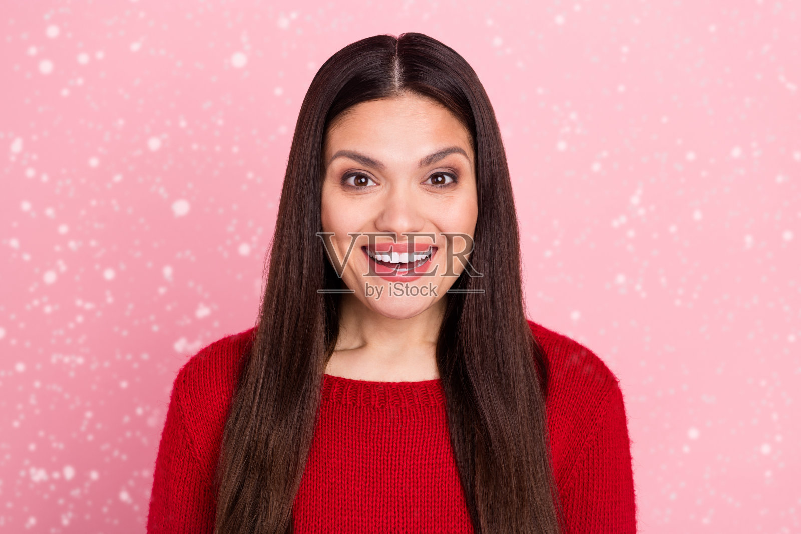 兴奋的可爱女孩对促销反应感到惊讶，灿烂的笑容，穿着红色毛衣，背景为粉色。照片摄影图片