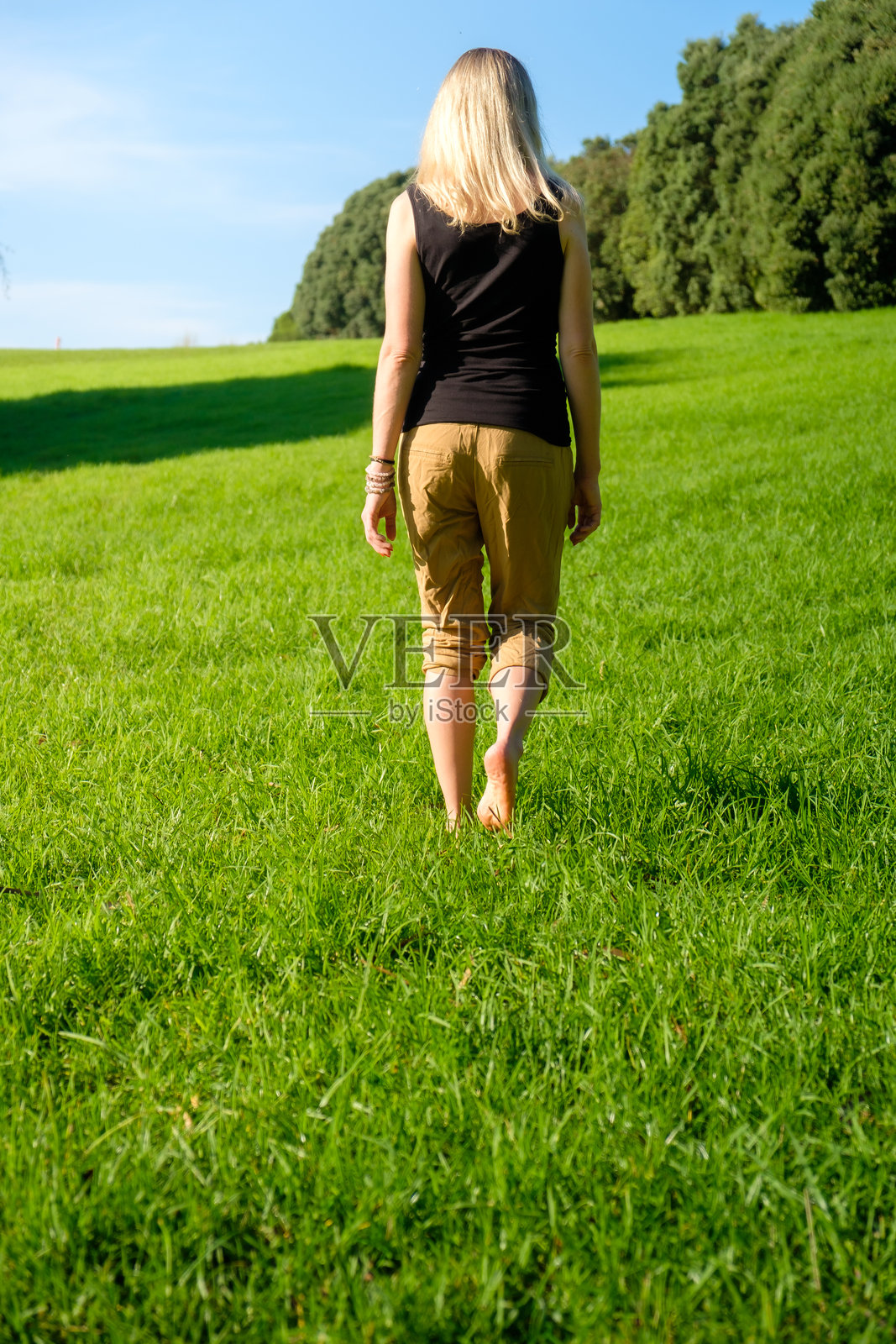 赤脚在草地上行走的女人。接地/大地疗法照片摄影图片
