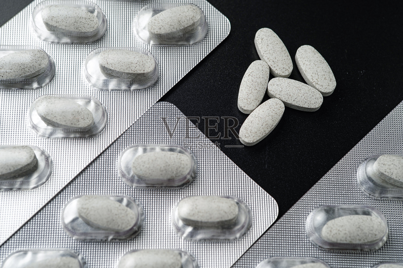 黑色背景上的抗生素白色药丸药片胶囊，装在泡罩包装中照片摄影图片