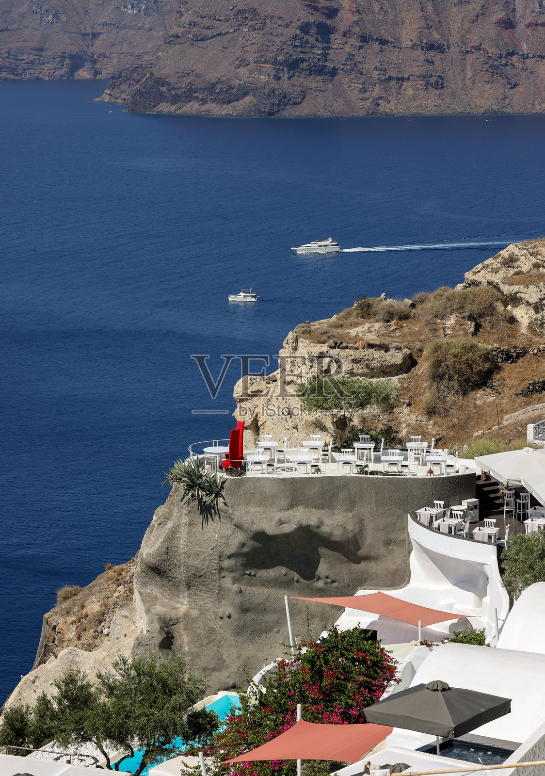 餐厅露台上的桌子,俯瞰着希腊圣托里尼岛奥伊亚的迷人日落景色。照片摄影图片