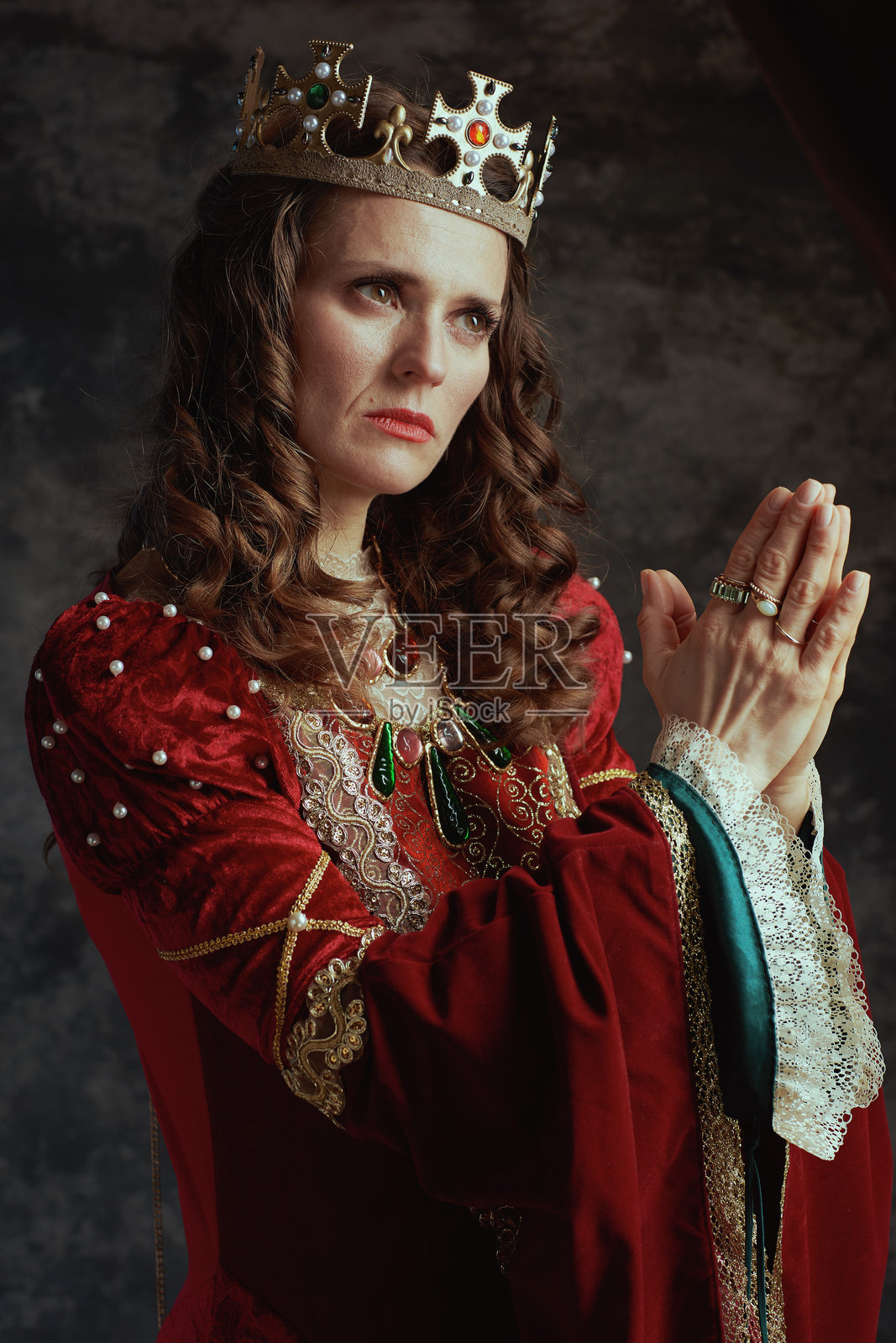 穿着红色裙子和王冠的中世纪女王在祈祷照片摄影图片