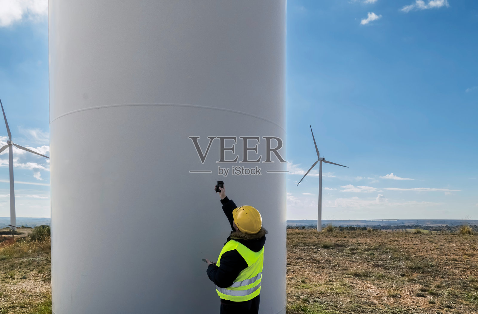 女性工程师在风电场使用移动设备检查风力涡轮塔照片摄影图片