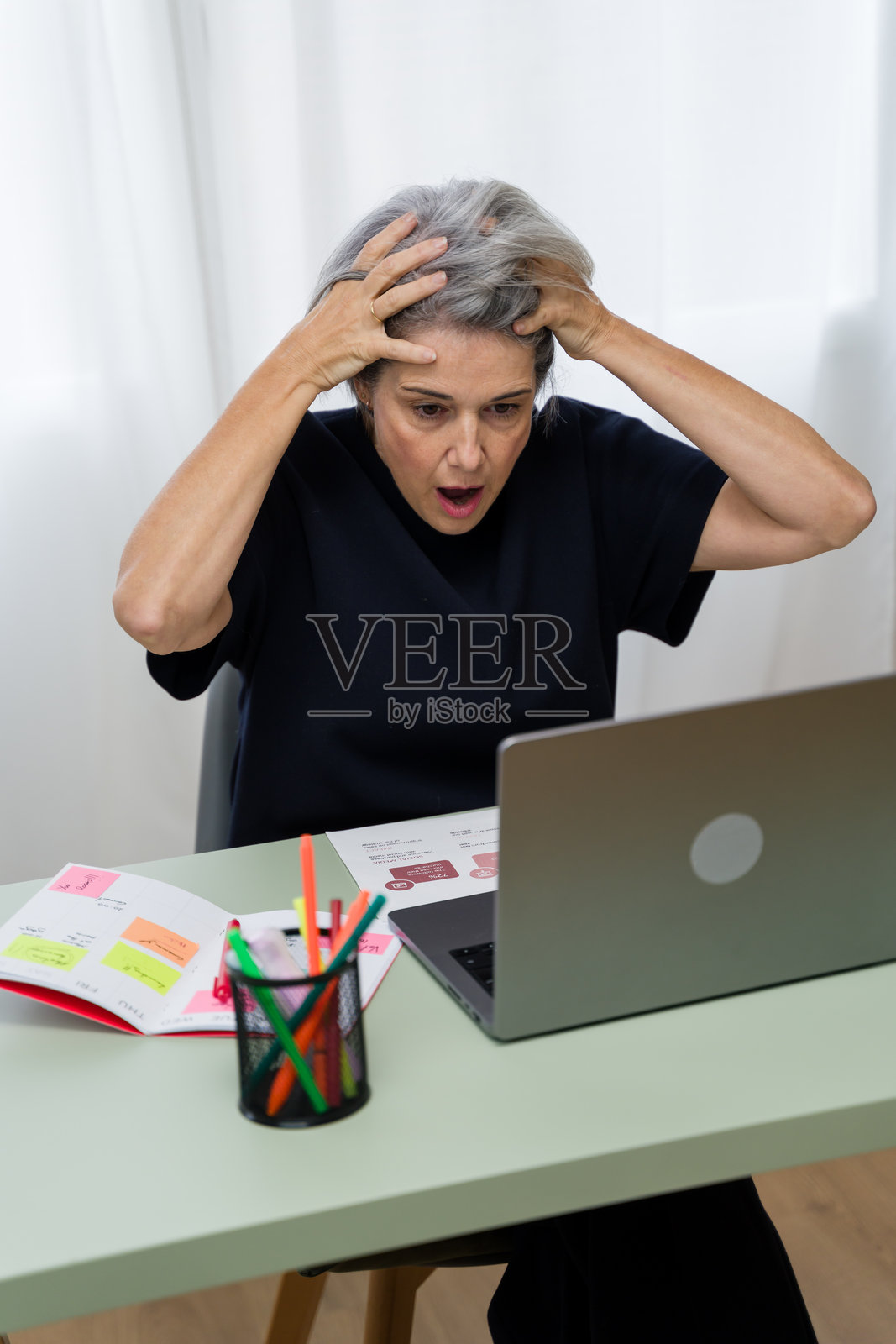 感到压力的女高管双手托着头，正在使用笔记本电脑工作照片摄影图片