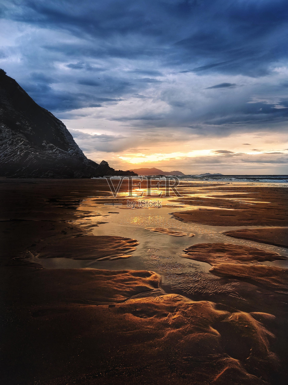 海滩上的日落，潮水的水洼中满是金色的倒影照片摄影图片