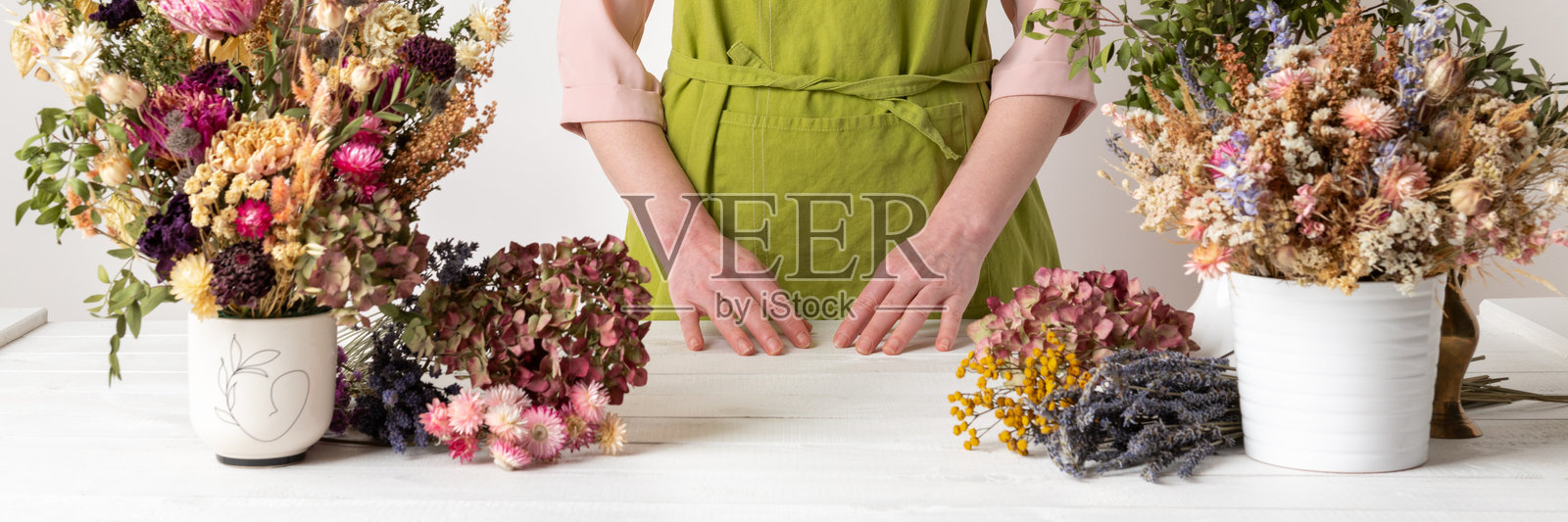 干花。女性花艺师将干花整理成美丽的花束。可持续花艺。用干花制作家居装饰。照片摄影图片